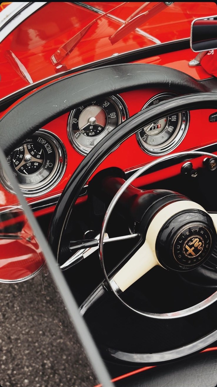 Dashboard and steering wheel of a red Alfa Romeo Giulietta at a Cars & Coffee Montenegro meet
